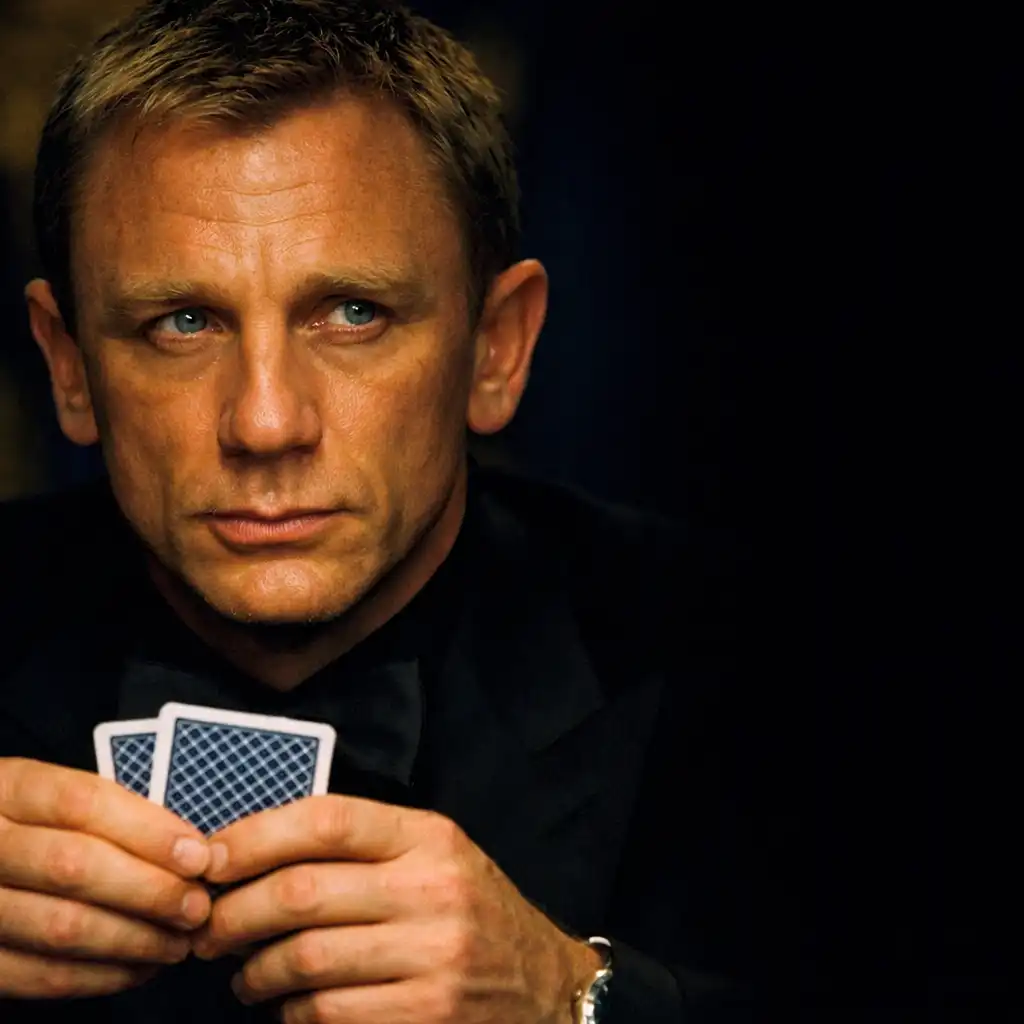 Kadr z filmu Casino Royale: Daniel Craig jako James Bond siedzi przy stole pokerowym, trzyma karty